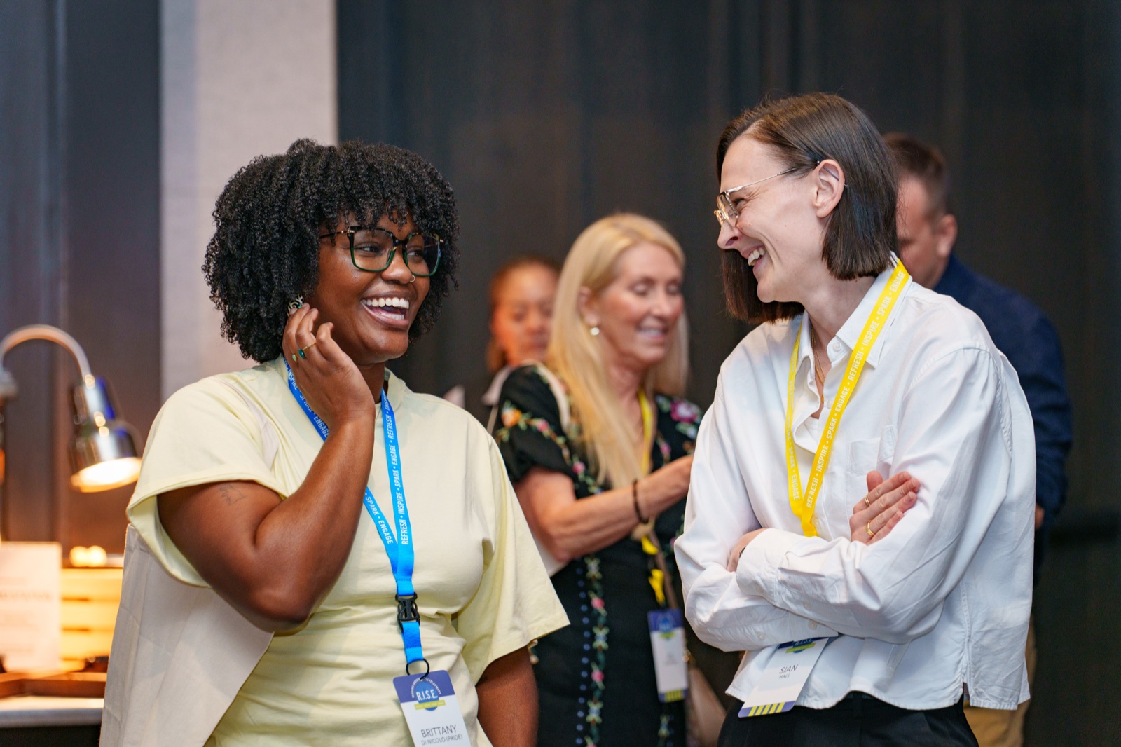 Two conference attendees laughing between sessions at a corporate event in Dallas