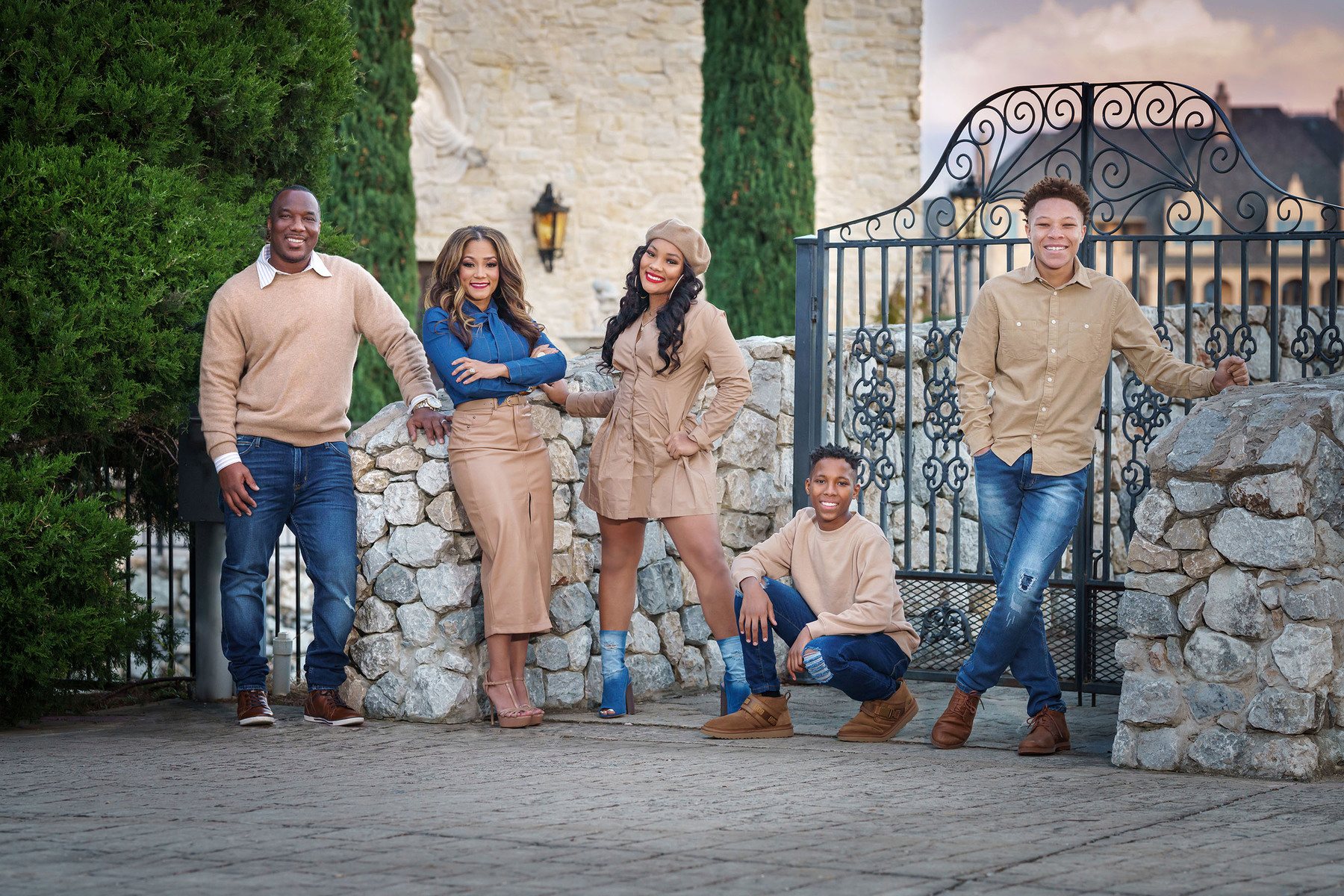 Family of five in front of a stone wall and iron gate