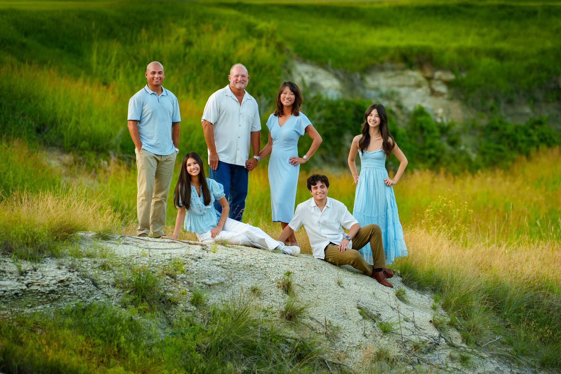 Family of six on a grassy hillside in soft evening light