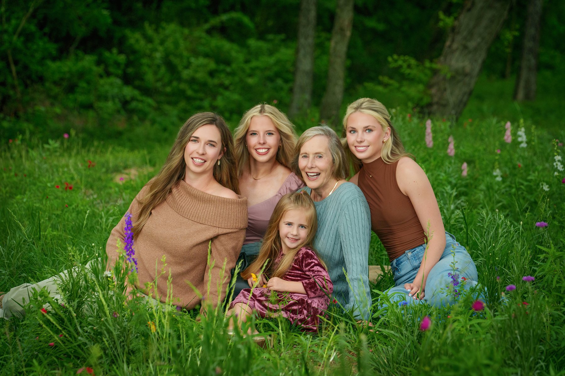 Grandmother, daughters and granddaughter sitting in a wildflower meadow