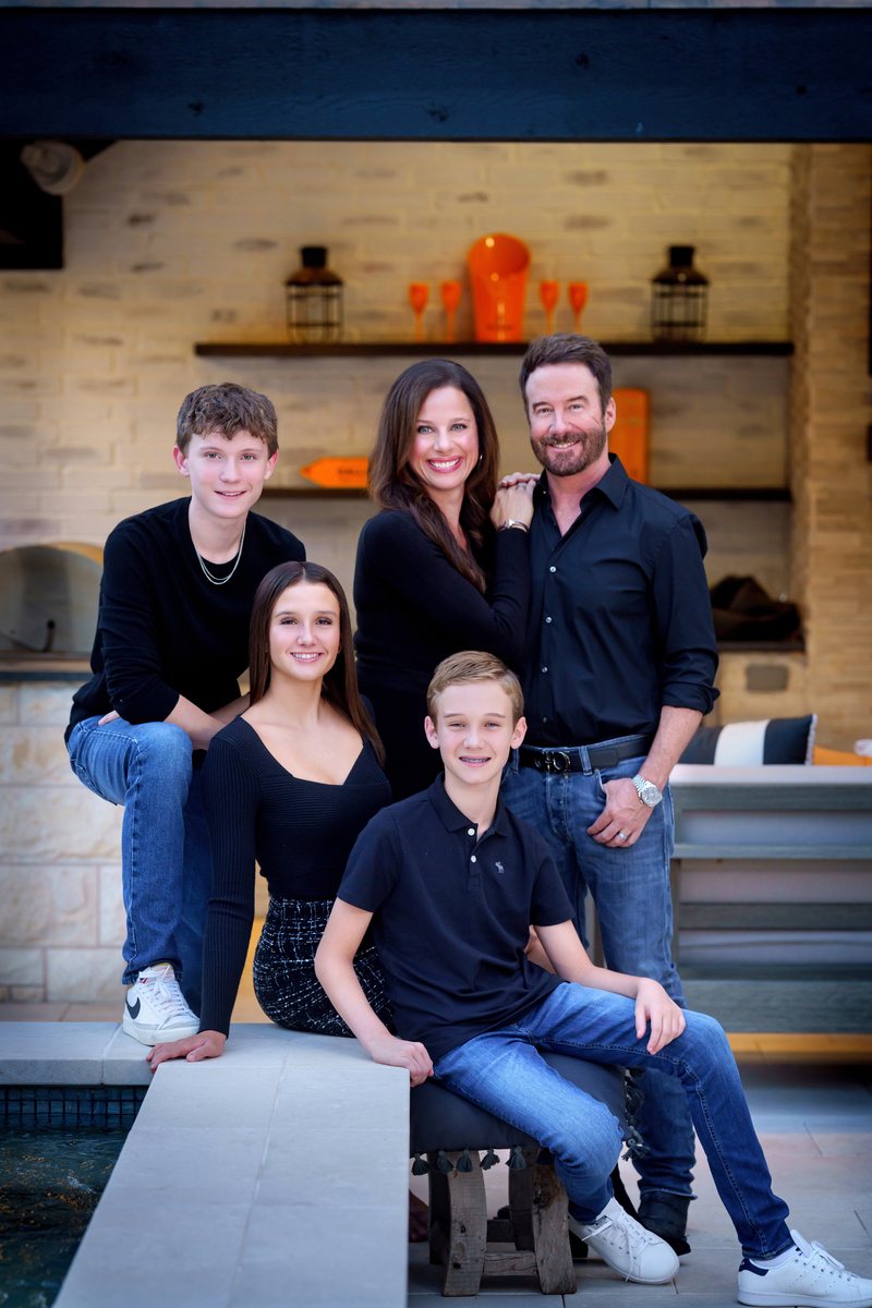 Family of five on an outdoor patio in front of a stone fireplace