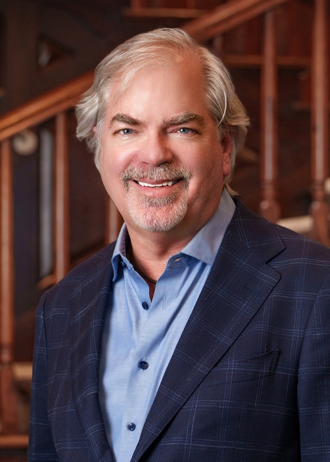 Executive headshot of a man in a navy check jacket