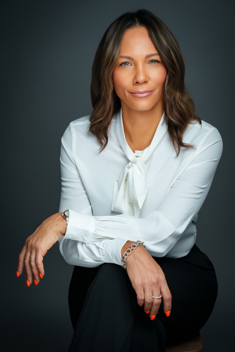 Studio headshot of a businesswoman seated on a dark grey background, McKinney TX