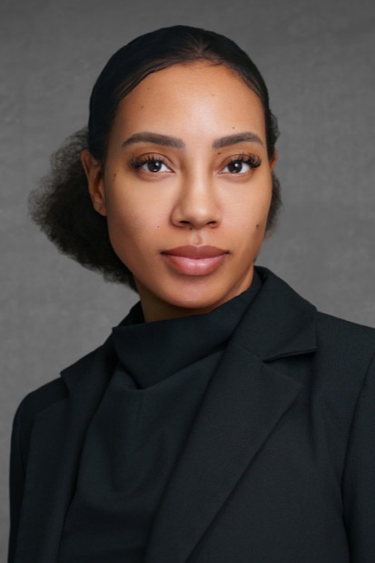 Studio headshot of a woman in a black jacket on a grey background
