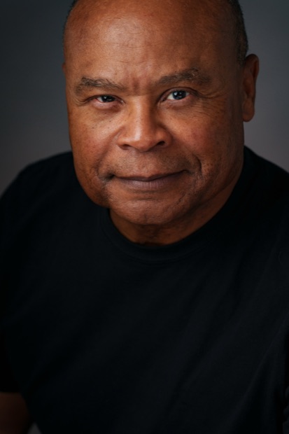 Studio headshot of a man in a black shirt on a dark background