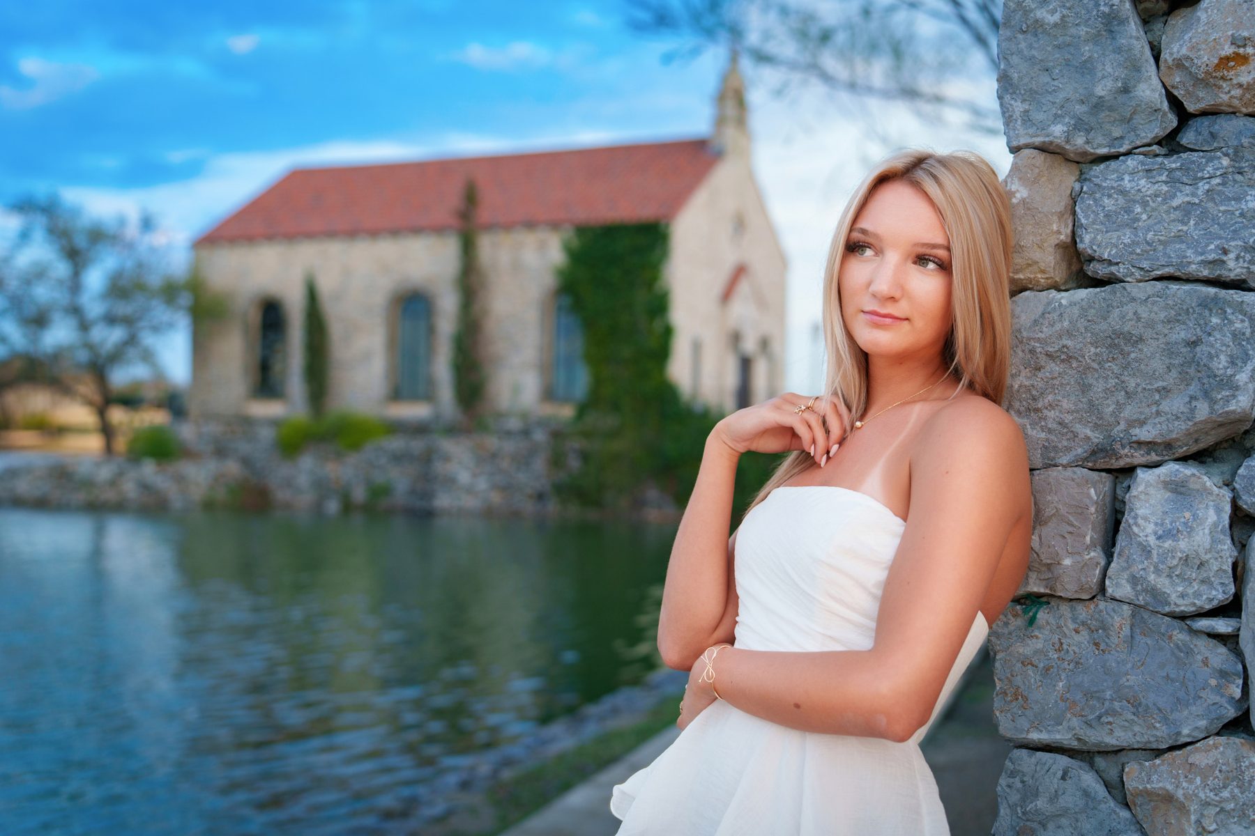 Senior portrait at the lakefront beside a stone chapel